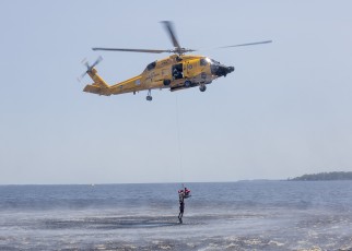 Rescue Swimmer Kyle McCollum AST3 stabilizes the basket while hoisting a USCG Cadet during training exercise at Coast Guard Air Station Elizabeth City, NC (Additional flight crew of MH-60T; Aircraft Commander -  CDR Scott Jackson, Co-Pilot - LT Dennis Stenkamp, Flight Mechanic Justin Lawrence AMT3 ).