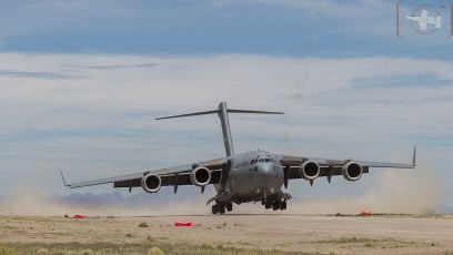 Air Mobility Command C-17A of the 436th AW/512 AW, Dover, DE kicks up the dust as it lands at Keno Airfield on the NTTR during Joint Forcible Entry Exercise (June 2016). Residue of rocket flares launched from ground are visible in the background.