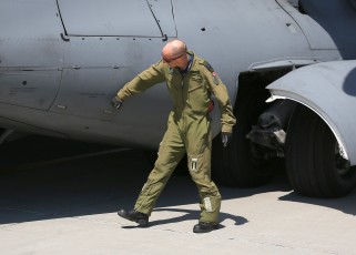 The aircraft commander, Maj. Hirt, inspects the landing gear of the CC-117 during his pre-flight walk-around.