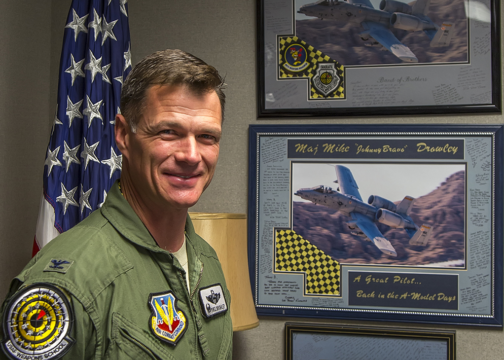 Colonel Michael "Johnny Bravo" Drowley, Commandant of the USAF Weapons School, stands in front of memorabilia recognizing his expertise as A-10 pilot.